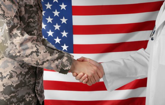 Soldier and doctor shaking hands on American flag background